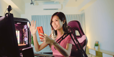 woman waving during a livestream with cellular and microphone