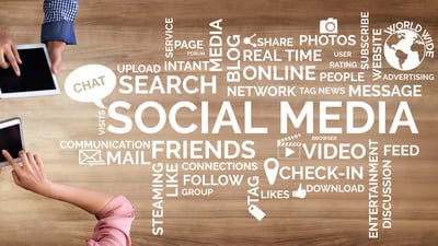 social media words and icons in white on wood background with cell phone and tablet